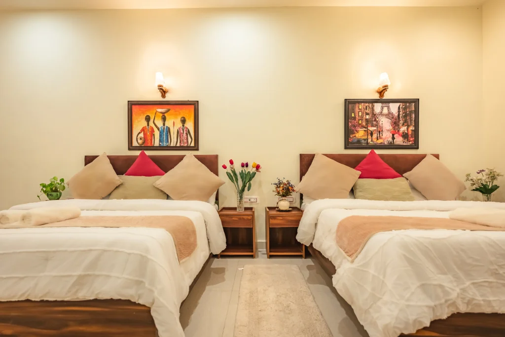 Cozy double-bed luxury room at Pristine Woods, a Luxury Resort in Dehradun, featuring two plush beds, elegant wooden furniture, tasteful wall art, soft lighting and a warm, comfortable ambience ideal for a relaxing stay.