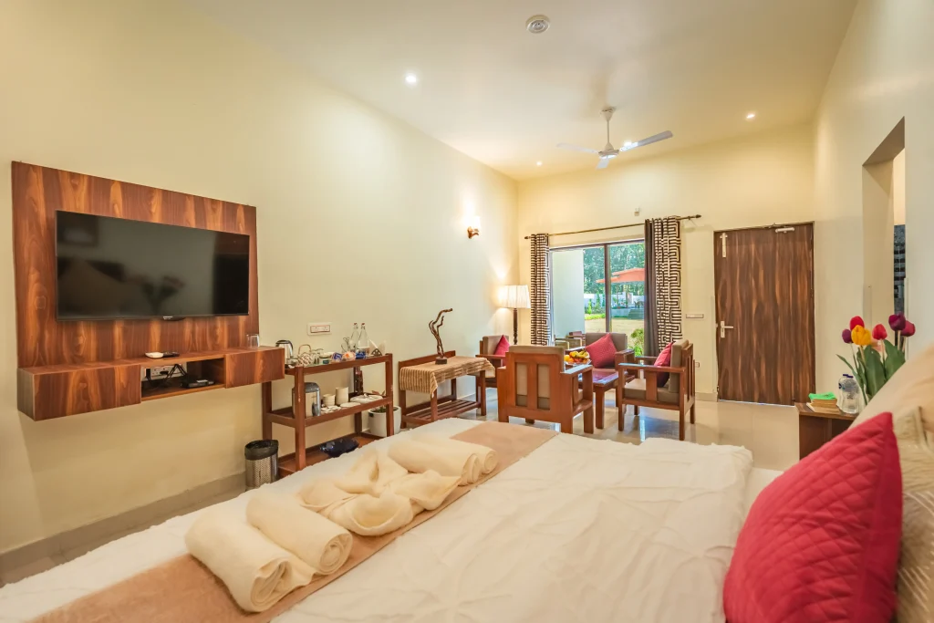 Elegant deluxe room interior at Pristine Woods, the Best Resort in Dehradun, featuring a king-size bed, modern seating area, private verandah and serene garden views for a luxury stay.