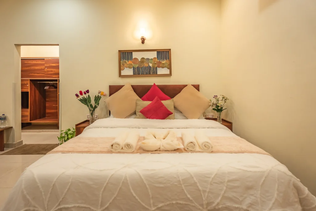 Comfortable deluxe bedroom at Pristine Woods, the Luxury Resort in Dehradun, featuring a plush king-size bed, elegant décor, soft lighting and premium furnishings for a peaceful luxury stay.