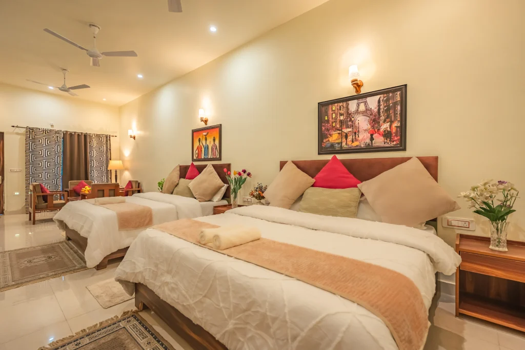Luxury double deluxe room at Pristine Woods, a Luxury Resort in Dehradun, featuring two plush beds, elegant wooden furniture, soft ambient lighting, wall art and a spacious layout ideal for family and group stays.