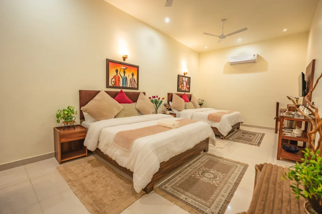 Spacious double deluxe room at Pristine Woods, a Luxury Resort in Dehradun, featuring two plush beds, elegant wooden furniture, warm lighting, modern amenities and a serene ambience ideal for family and group stays.