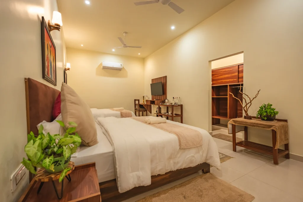 Elegant double deluxe room at Pristine Woods, a Luxury Resort in Dehradun, featuring twin plush beds, refined wooden interiors, modern amenities, spacious wardrobe area and a calm ambience ideal for families and group stays.