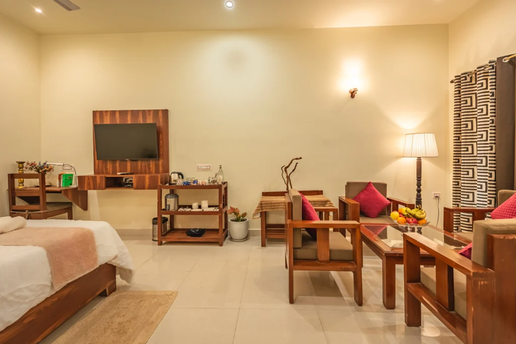 Spacious luxury room at Pristine Woods, the Best Resort in Dehradun, featuring a comfortable king-size bed, elegant seating area, modern TV unit, warm lighting and premium amenities for a refined resort stay.