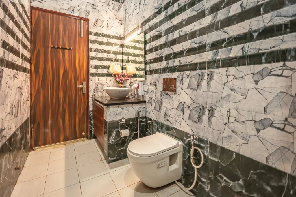 Modern, hygienic bathroom at Pristine Woods, a Luxury Resort in Dehradun, featuring premium marble-finish tiles, contemporary washbasin, elegant fittings and well-maintained amenities for a comfortable and relaxing stay.