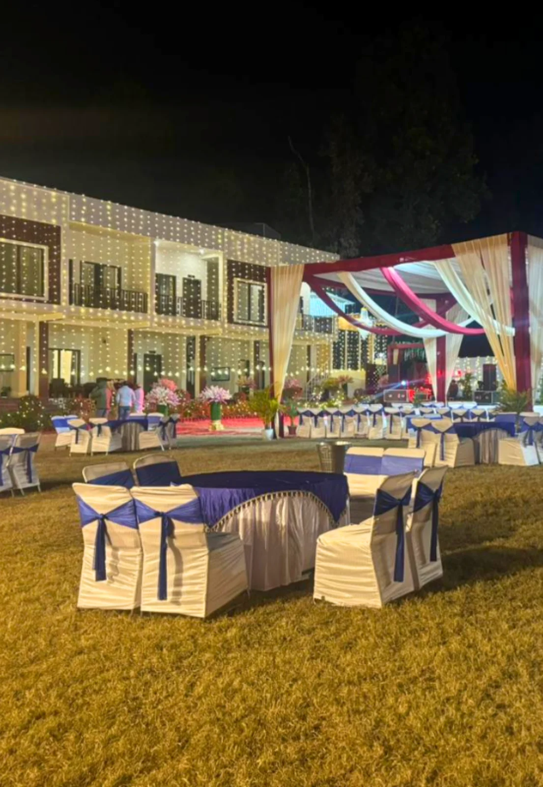Beautifully decorated outdoor wedding venue in Dehradun at Pristine Woods Resort with banquet seating, floral stage setup and illuminated lawn decor