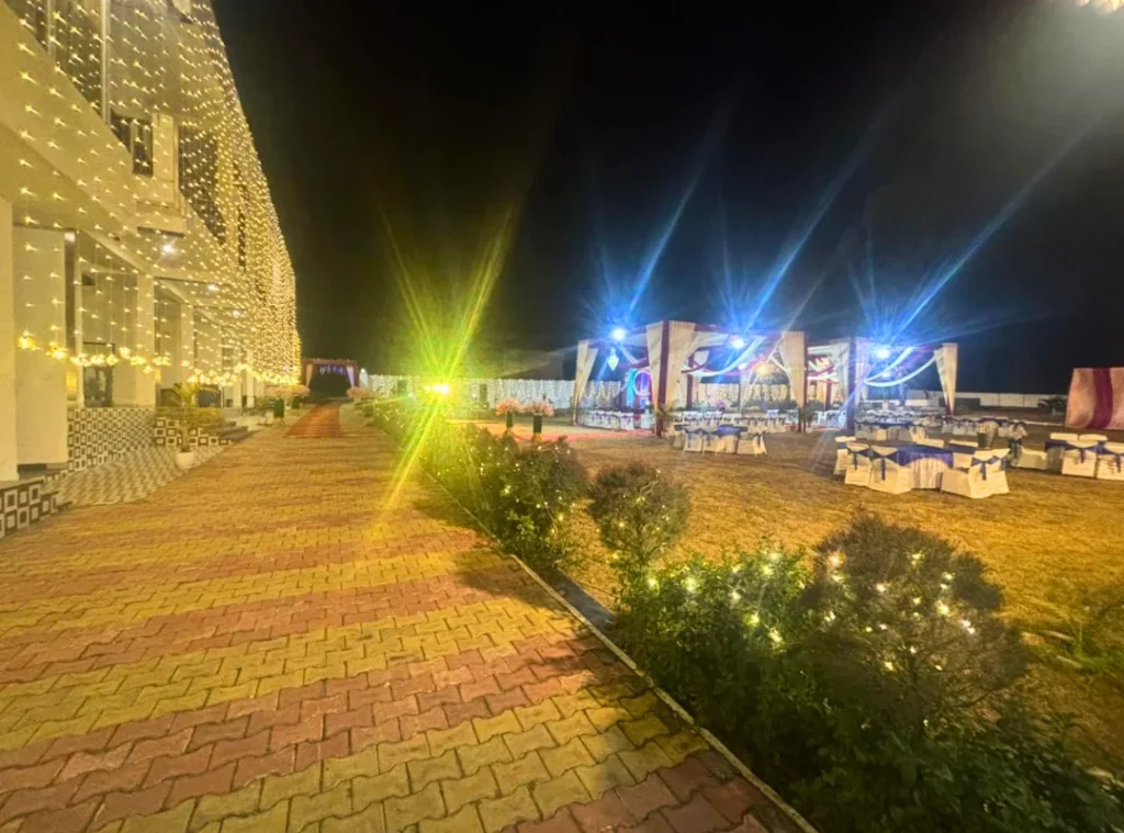 Spacious outdoor wedding venue in Dehradun featuring decorated lawn, canopy stage and illuminated resort building