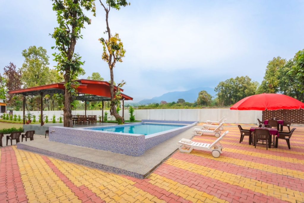 Swimming pool area at Pristine Woods resort in Dehradun surrounded by nature and mountain views