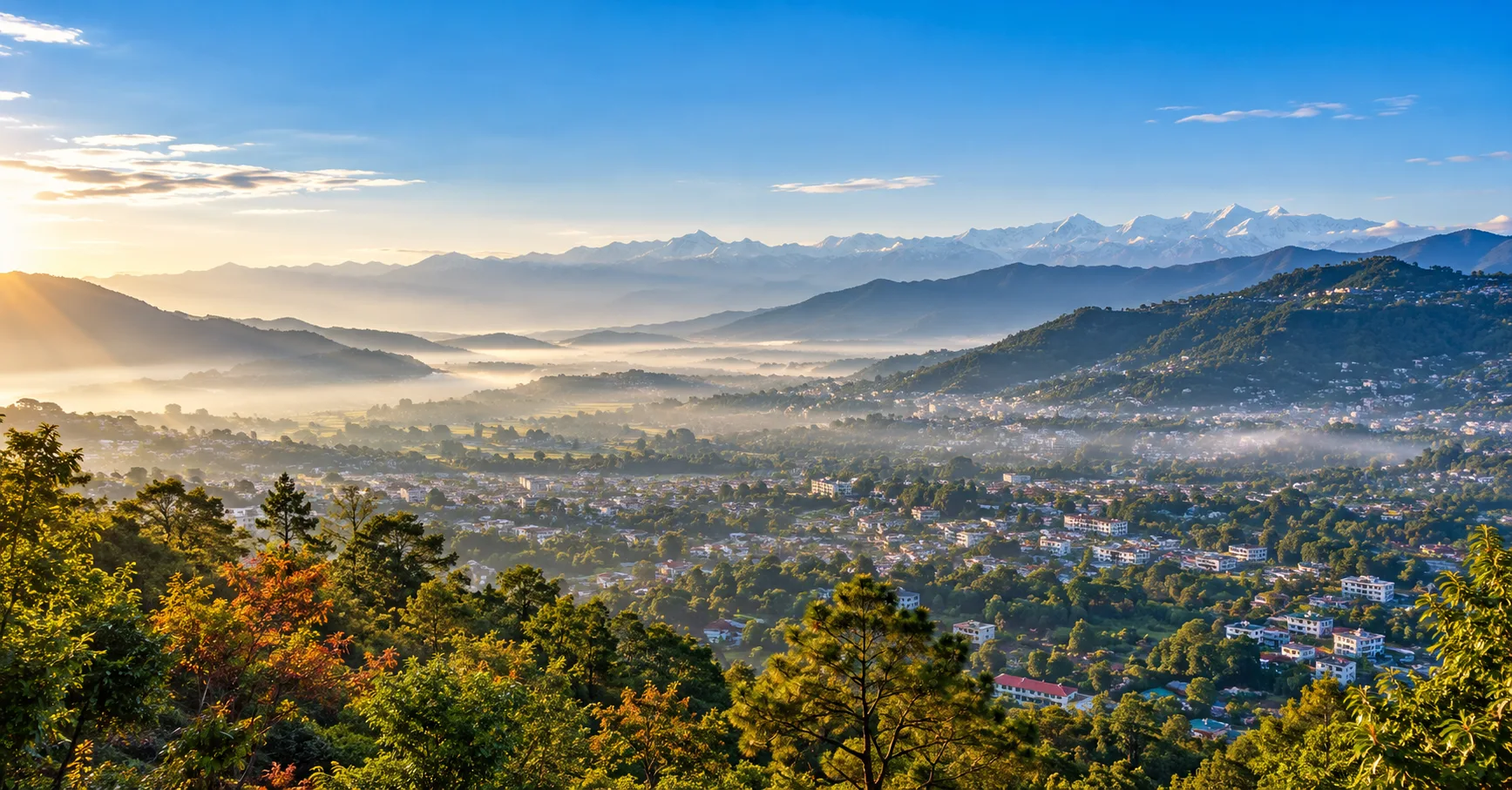 Dehradun in December with a clear winter sky, misty Doon Valley, and distant Himalayan mountain views.